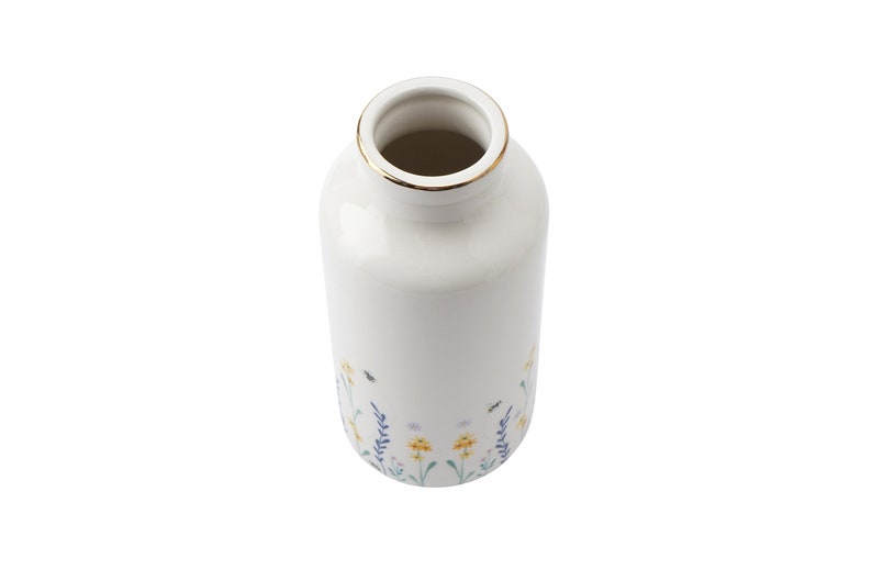 May include: White ceramic vase with a gold rim and a floral pattern featuring yellow flowers, green leaves, and blue stems. The vase has a narrow cylindrical shape.