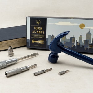 May include: A blue 6-in-1 hammer and screwdriver set with a cityscape design on the box. The set includes a hammer, a screwdriver, and four interchangeable screwdriver bits. The box says "Tough as Nails" and "Gentlemen's Essentials".