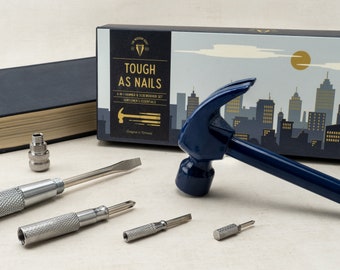 May include: A blue 6-in-1 hammer and screwdriver set with a cityscape design on the box. The set includes a hammer, a screwdriver, and four interchangeable screwdriver bits. The box says "Tough as Nails" and "Gentlemen's Essentials".