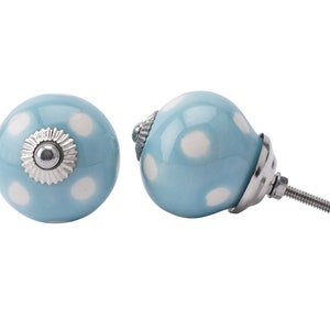 Peut inclure: Deux boutons de cabinet en céramique bleue avec des pois blancs. Un bouton a une vis argentée et l'autre a une base argentée.