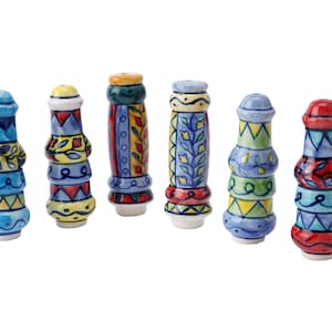 Pode incluir: Seis rolhas de garrafa de cerâmica coloridas com padrões intrincados. Cada rolha apresenta um design diferente com uma mistura de azul, vermelho, amarelo, verde e branco.