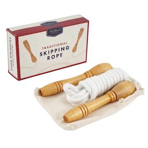 Pode incluir: Um conjunto de corda de saltar tradicional com cabos de madeira e uma corda branca, apresentado numa caixa decorativa. A caixa é vermelha e branca com as palavras "Traditional Skipping Rope".