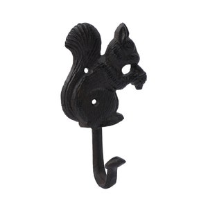 May include: Black cast iron squirrel hook. The hook is shaped like a squirrel holding a nut, with a curved hook at the bottom. The squirrel has a textured surface and two holes for mounting. Perfect for a rustic or woodland-themed decor.