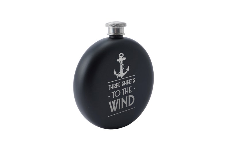 May include: Black metal flask with a silver anchor and the text "Three Sheets To The Wind".