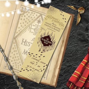 May include: A bookmark with The Marauder's Map design, including the text "Moony, Wormtail, Padfoot & Prongs" and "I solemnly swear that I am up to no good...". The bookmark is placed on an open book, with a wand and a scarf.