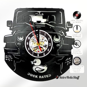 May include: Black vinyl record clock shaped like a Jeep, featuring a clock face with visible gears. The clock has red and black hands, and the text "DUCK RATED" is visible. The clock is 12 inches in diameter.