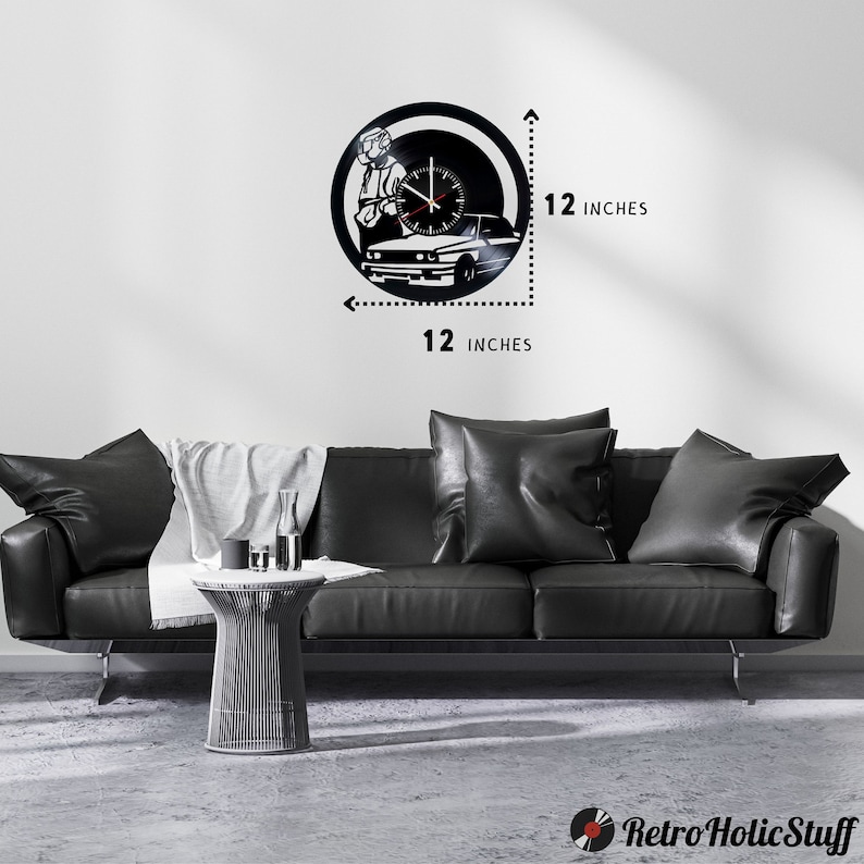 May include: Black vinyl record clock featuring a silhouette of a person sitting in a car. The clock is 12 inches in diameter.