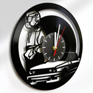 May include: A black vinyl record clock featuring a silhouette of a person in a spacesuit, a car, and a clock face with white hands and red second hand.