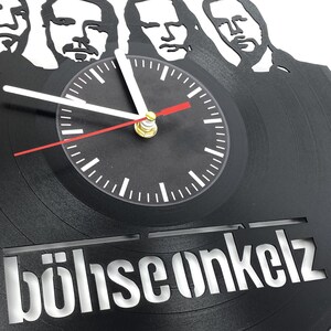 Close-up of Böhse Onkelz vinyl record clock showing detailed cutout portraits of band members above the central clock face.