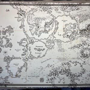 May include: A detailed black and white fantasy map with intricate illustrations of landmasses, seas, and geographical features. The map includes compass rose, place names like 'Aurorans' and 'Seleni', and is framed with a decorative border.