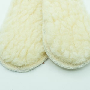 May include: Two white, round, fluffy, sheepskin pads with a light gray trim.