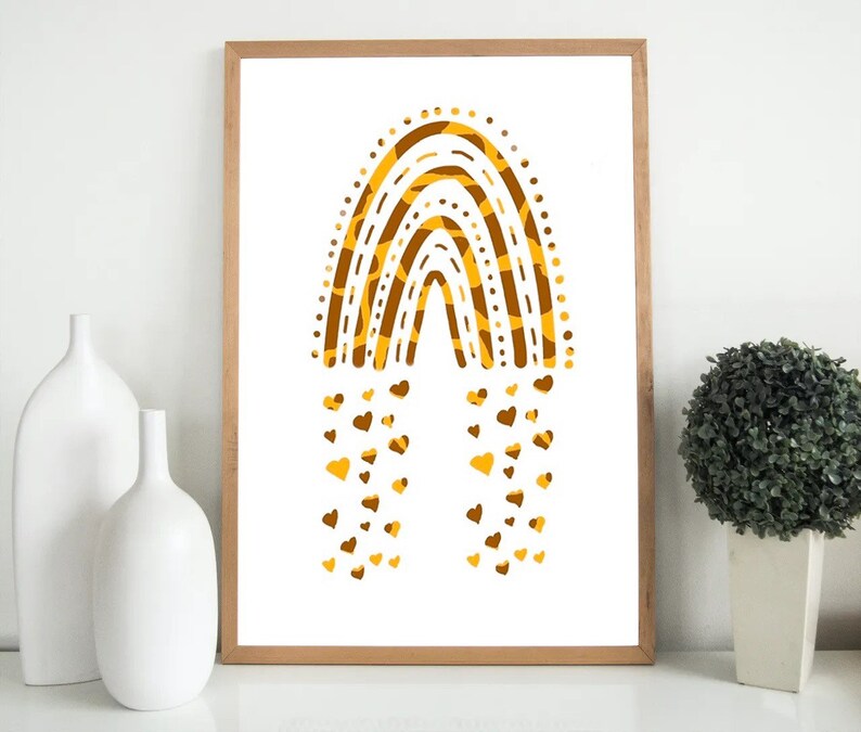 May include: A framed art print featuring a stylized rainbow design in shades of brown and yellow. The rainbow is composed of layered arches with a dotted border and a textured pattern. Small heart shapes cascade from the bottom of the rainbow.