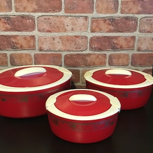 May include: Three red and white insulated food storage containers with lids. The containers are round and have a white rim around the top. The lids have a white handle and a white latch on the side.