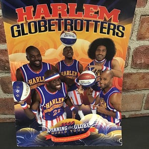 May include: A promotional poster for the Harlem Globetrotters 2009 World Tour. The poster features five basketball players in blue and red uniforms, holding basketballs. The words "HARLEM GLOBETROTTERS" are prominently displayed at the top.