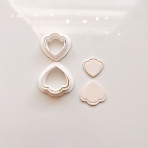 May include: A set of three white plastic flower cookie cutters and two white fondant flower shapes.