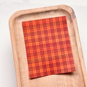 May include: A red and orange plaid fabric sheet on a wooden tray.