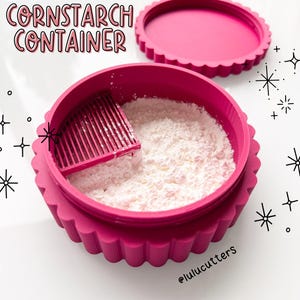 Puede incluir: Un recipiente de almidón de maíz rosa brillante con tapa roscada. El recipiente está lleno de almidón de maíz blanco y tiene un tamiz. El texto de la imagen dice "threaded lid CORNSTARCH CONTAINER" y "The lid screws on, securing the cornstarch inside! Available in several colors."