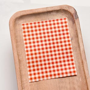 Puede incluir: Un cuadrado de tela de cuadros rojos y blancos sobre una bandeja de madera.