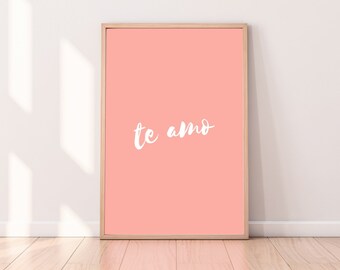 Könnte beinhalten: Ein gerahmter Druck mit einem pfirsichfarbenen Hintergrund und dem Text "te amo" in weißer Kursivschrift.