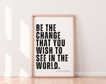 Könnte beinhalten: Ein Schwarzweiß-Motivationszitat in einem Holzrahmen. Das Zitat lautet "Sei die Veränderung, die du in der Welt sehen möchtest." Das Zitat wird Mahatma Gandhi zugeschrieben.