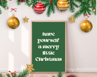 Könnte beinhalten: Eine grüne Tafel mit dem Text "have yourself a merry little Christmas" in weiß. Die Tafel ist von Weihnachtskugeln und Grün umgeben.