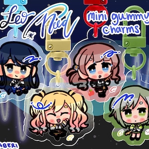 May include: Five acrylic charms with anime-style character designs. Each charm has a different character, with varying hair colours and outfits. The charms are attached to coloured clasps and feature the text "Leo/Need" and "mini gummy charms".
