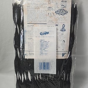 Puede incluir: Un paquete de tallos de chenilla negros con puntas blancas, perfecto para manualidades. El embalaje incluye instrucciones sobre cómo vestir muñecas, con ilustraciones y texto. La marca "Chenille Kraft" es visible.