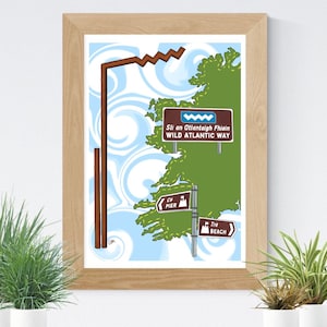 May include: A framed art print featuring a stylized map of Ireland with the text "Wild Atlantic Way." The artwork includes brown signposts pointing to locations like "Pier" and "Beach," set against a blue and white swirling background.