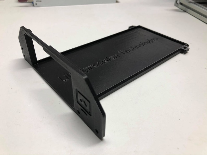 May include: A black plastic 3D printed frame with the text "Ultraprecision Technologies" printed on the top surface.