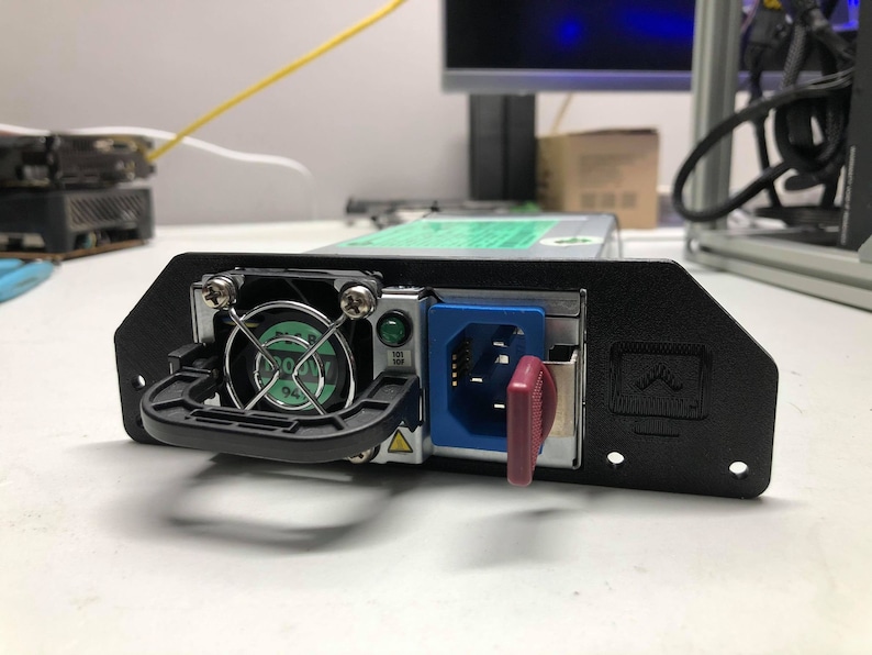 May include: A black computer power supply unit with a green fan, a blue power cord, and a red key switch. The unit has a handle and is mounted on a black bracket.