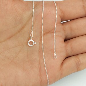Pode incluir: Uma corrente de colar fina de cor prateada com elos tipo grumet e um pequeno fecho de mola circular. A delicada corrente de metal consiste em elos ovais ligeiramente achatados que criam uma superfície metálica lisa, contínua e reflexiva.