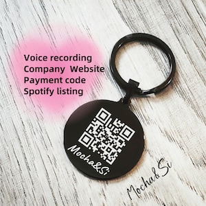 May include: Black metal keychain with a round tag featuring a black and white QR code and the text "Mocha&Si". The keychain has a silver ring.