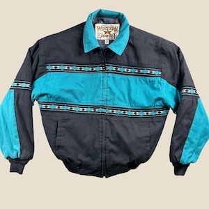May include: A black and teal zip-up jacket featuring a collar, long sleeves, and a horizontal patterned band across the chest and sleeves. The interior label displays the text Western Frontier with a star graphic. The jacket has a full front zipper.