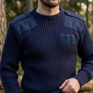 Könnte beinhalten: Marineblauer Rippstrickpullover mit verstärkten Schulteraufnähern und einer Brusttasche. Der Pullover hat einen Rundhalsausschnitt und ein klassisches, strapazierfähiges Design, geeignet für Outdoor-Aktivitäten oder Freizeitkleidung.