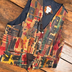 May include: A sleeveless vest constructed from a patchwork of multi-colored leather pieces in shades of red, yellow, brown, green, and black. The garment features a front button closure, two lower pockets, and a dark interior lining with a J.M.G. label.