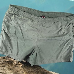 May include: Olive green shorts with an elastic waistband. The shorts are made of a lightweight material and have a relaxed fit. The shorts are suitable for casual wear or outdoor activities.