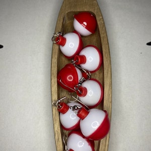 May include: A set of six red and white bobber earrings. The bobbers are made of plastic and have a silver hook.