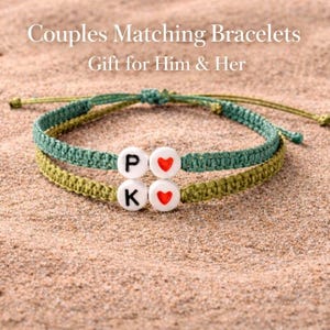May include: Two matching macrame bracelets, one green and one olive, with white letter beads spelling "PK" and red heart beads. The bracelets are displayed on a sandy surface, with the text "Couples Matching Bracelets" and "Gift for Him & Her" in the background.