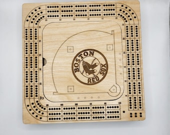 May include: Wooden cribbage board with a baseball field design. The board features the Boston Red Sox logo and a scoring area.