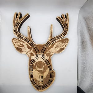 May include: Wooden deer head game board with a brown and white deer image and black dots. The board has a "Winner" label at the bottom.