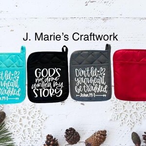 May include: Four quilted pot holders with different colors and inspirational quotes. The quotes are "Don't let your heart be troubled - John 14:1", "God's not done writing my story", "Don't let your heart be troubled - John 14:1", and a blank red pot holder.