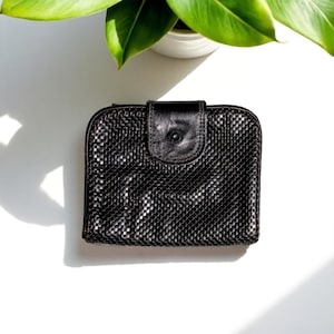 Porte-monnaie vintage en cuir noir de la marque GLOMESH et plié Glomesh - section pièces, cartes et billets.