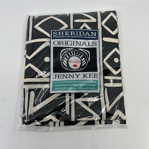 May include: A pair of black and white patterned pillowcases in a clear plastic wrapper. The pillowcases feature a geometric design. The label reads "SHERIDAN ORIGINALS JENNY KEE" and states the pillow size is 48cm x 73cm.