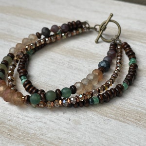 Multi strand, antique brass toggle clasp bracelet using glass, wood, metal and plated Hematite beads.