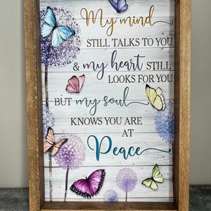 May include: Wooden framed sign with a white background and the text "My mind still talks to you & my heart still looks for you but my soul knows you are at peace." The sign features colorful butterflies and floral accents.