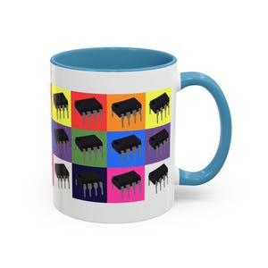 May include: A white ceramic mug with a light blue interior and handle. The mug features a colorful pattern of repeated images of an integrated circuit chip.