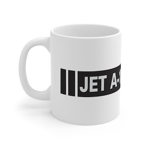 May include: White ceramic mug with a black rectangular design that reads "JET A-1" in white capital letters. The mug has a curved handle and a glossy finish. The mug is designed for hot or cold beverages.