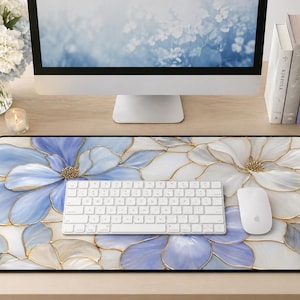 May include: A decorative mouse mat with a floral design in blue, white, and gold. The mat features a large flower pattern and a black border. A white keyboard and mouse are on the mat.