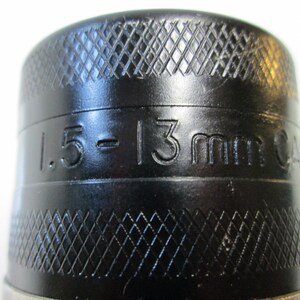 以下が含まれることがあります： 黒いドリルチャックのクローズアップ。側面に「1.5 - 13mm 24」と刻印されています。