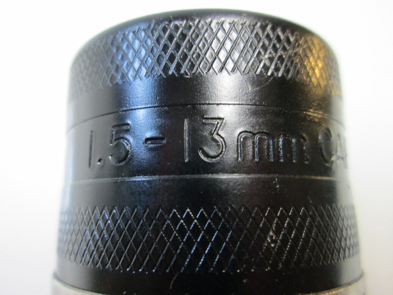 以下が含まれることがあります： 黒いドリルチャックのクローズアップ。側面に「1.5 - 13mm 24」と刻印されています。